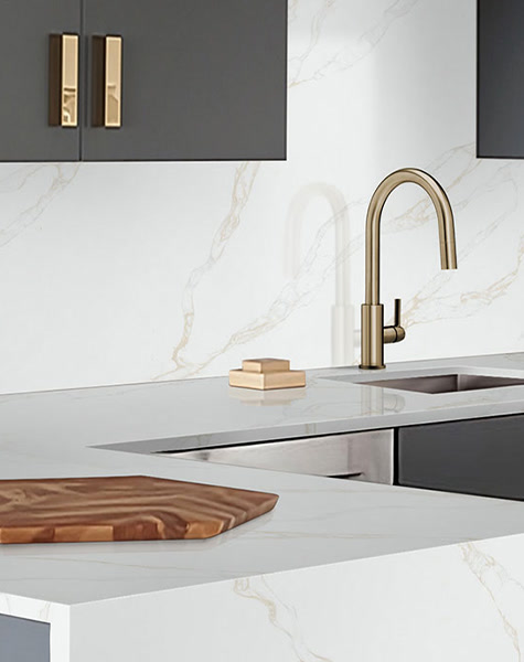 Veined white quartz countertop and backsplash with a brass faucet